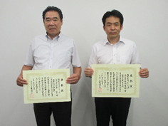 代表取締役の石倉氏と主任技術者の古川氏が表彰状を手にして並んでいる写真
