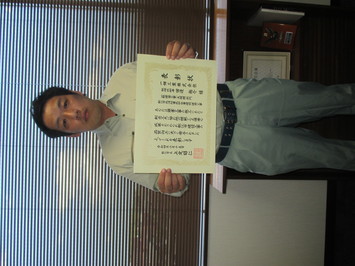 表彰状を持って正面に向けている一畑工業株式会社の田邊祐介氏の写真
