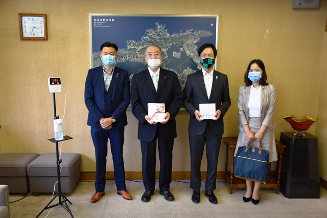 自動検温器セットと共に、目録を持っている松浦松江市長と、寄贈者の男女3人の写真