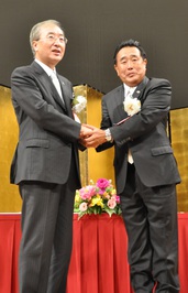 席の前に立ち握手を交わす鈴木町長と松浦市長の写真