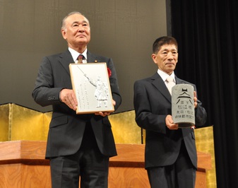 アルミプレートとインテリアライトをそれぞれ胸に抱く木野春徳議長と山本勝太郎議長の写真