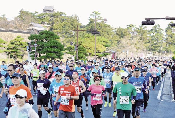松江城前を走り行く、松江城マラソン大会参加者たちの競技風景の写真