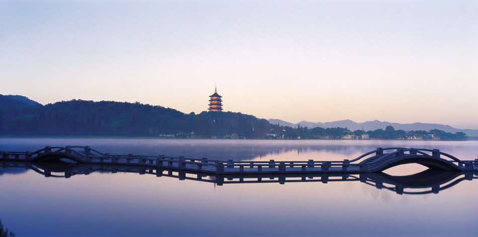 夕焼けに染まった西湖にかかっている橋と塔が写っている写真