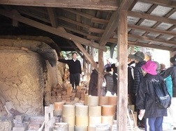楽山窯の横に立っている男性と窯の前に集まっている参加者の写真