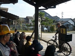 公園で昔ながらの紙芝居屋さんの紙芝居を見ている参加者の写真