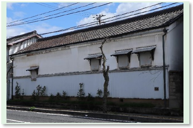 漆喰塗りの白色の壁に4か所の換気窓が施された「米田酒造貯蔵蔵」の建物外観の写真