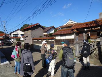 建物と道の間に水路があり建物の入り口に橋が渡してある、加賀のまちなみを見学している参加者の写真