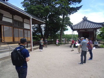 道栄寺の建物の前で話をしている住職さんと説明を聞いている参加者の写真