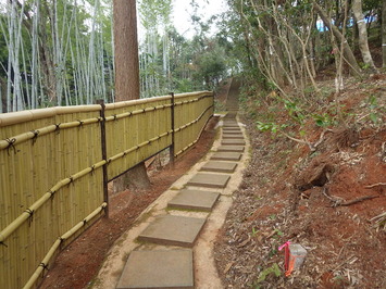 竹林と飛び石の道の間に垣根が設置された施工後の園路の写真