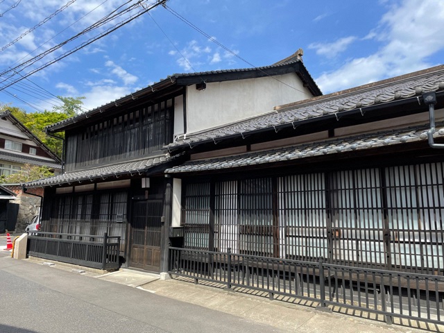 木造2階建てで窓に平格子が施されている「綿貫家住宅」の建物外観の写真