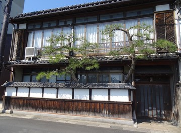 道路側に漆喰塀に松の木が立つ2階建ての旧料亭久の家の建物外観の写真