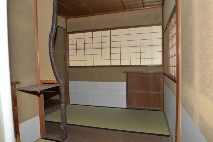 畳と畳の間に板の間があり障子の窓と壁には腰貼りが施された和室の写真