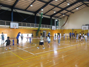 令和3年度の放課後子ども教室でのミニテニスの活動を写した写真、20人ほどの子どもたちが体育館でミニテニスを楽しんでいる