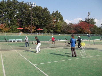 5人の男女がテニスコートの上でテニスをしている写真
