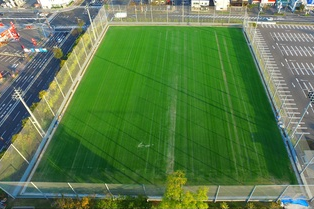 高いフェンスで囲まれた緑豊かな芝生のグラウンドを、上空から撮影した写真