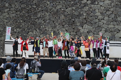 松江城の屋外のステージで2018松江だんだん夏踊り総踊りをしていて、観客がそれを見ている写真
