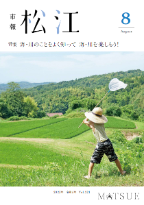 青々とした野山を麦わら帽子の少年が網を高く掲げて虫取りをする姿の写真です。