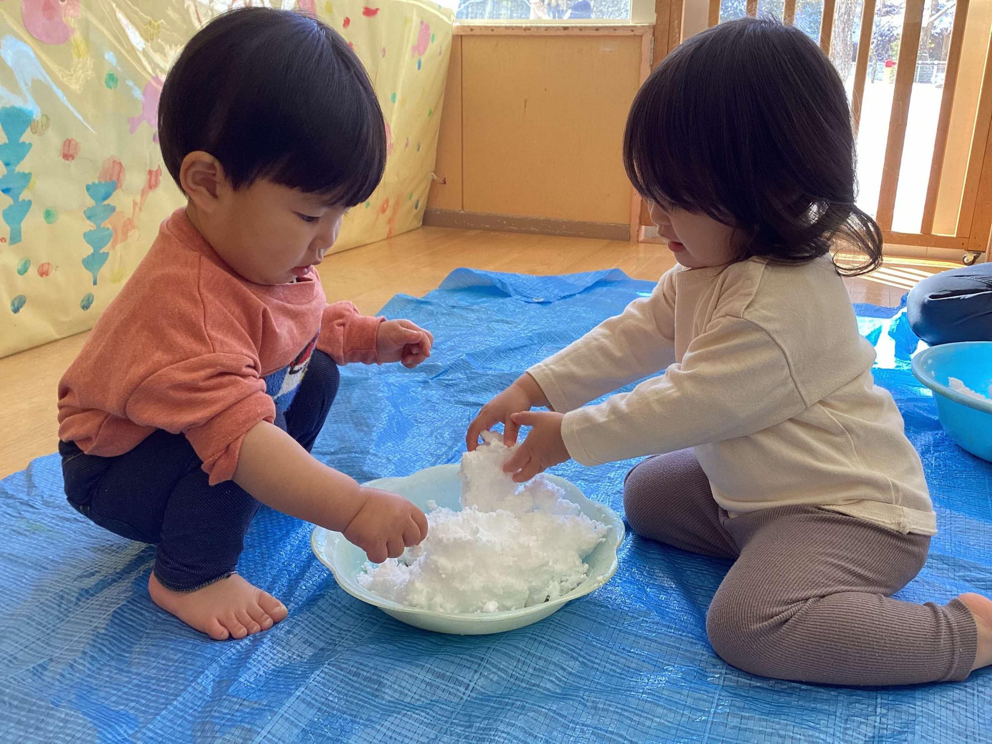 保育室で洗面器に雪を入れて遊んでいるところ