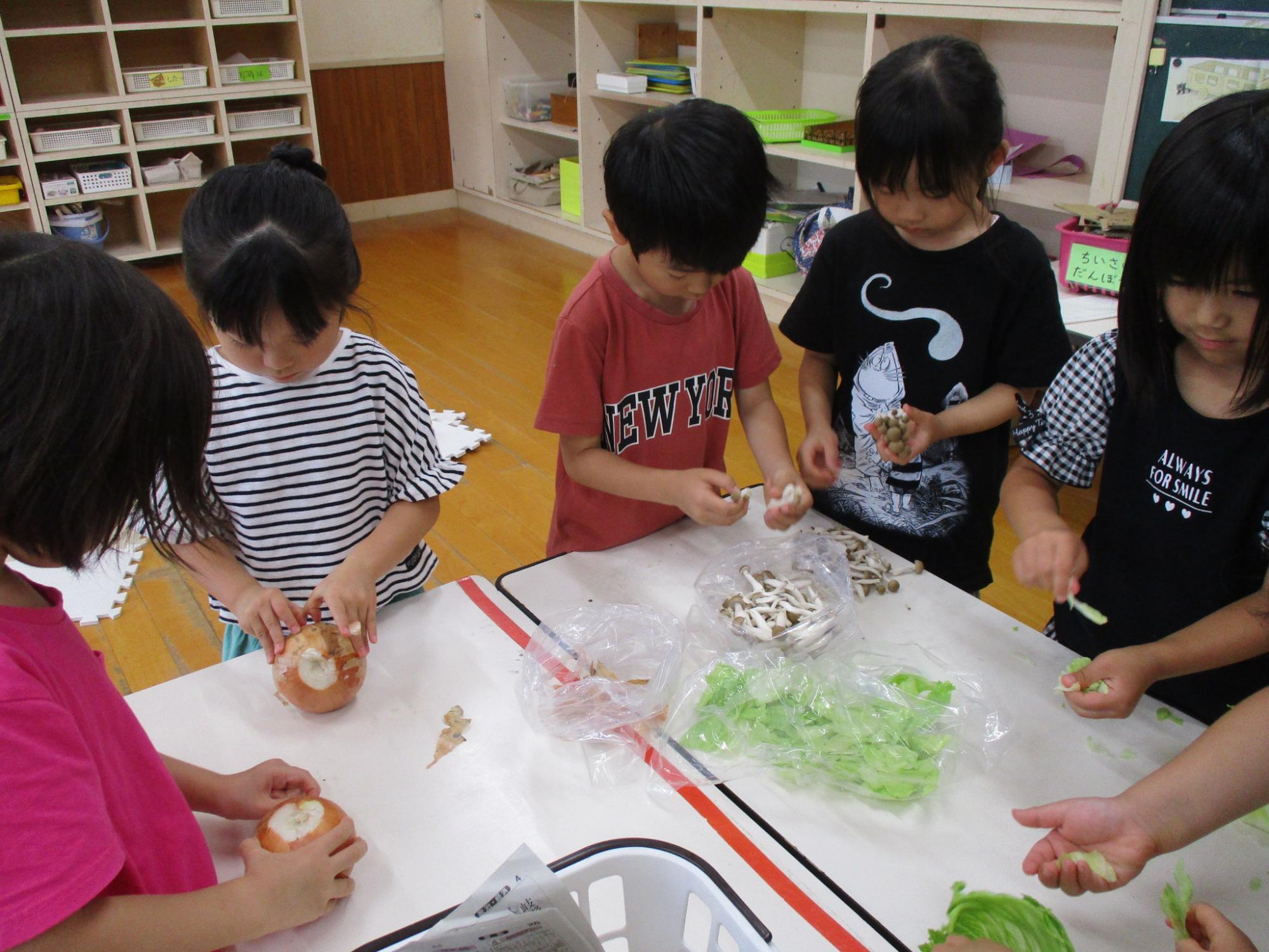 玉ねぎ、シメジ、レタスの給食お手伝いをする年長児