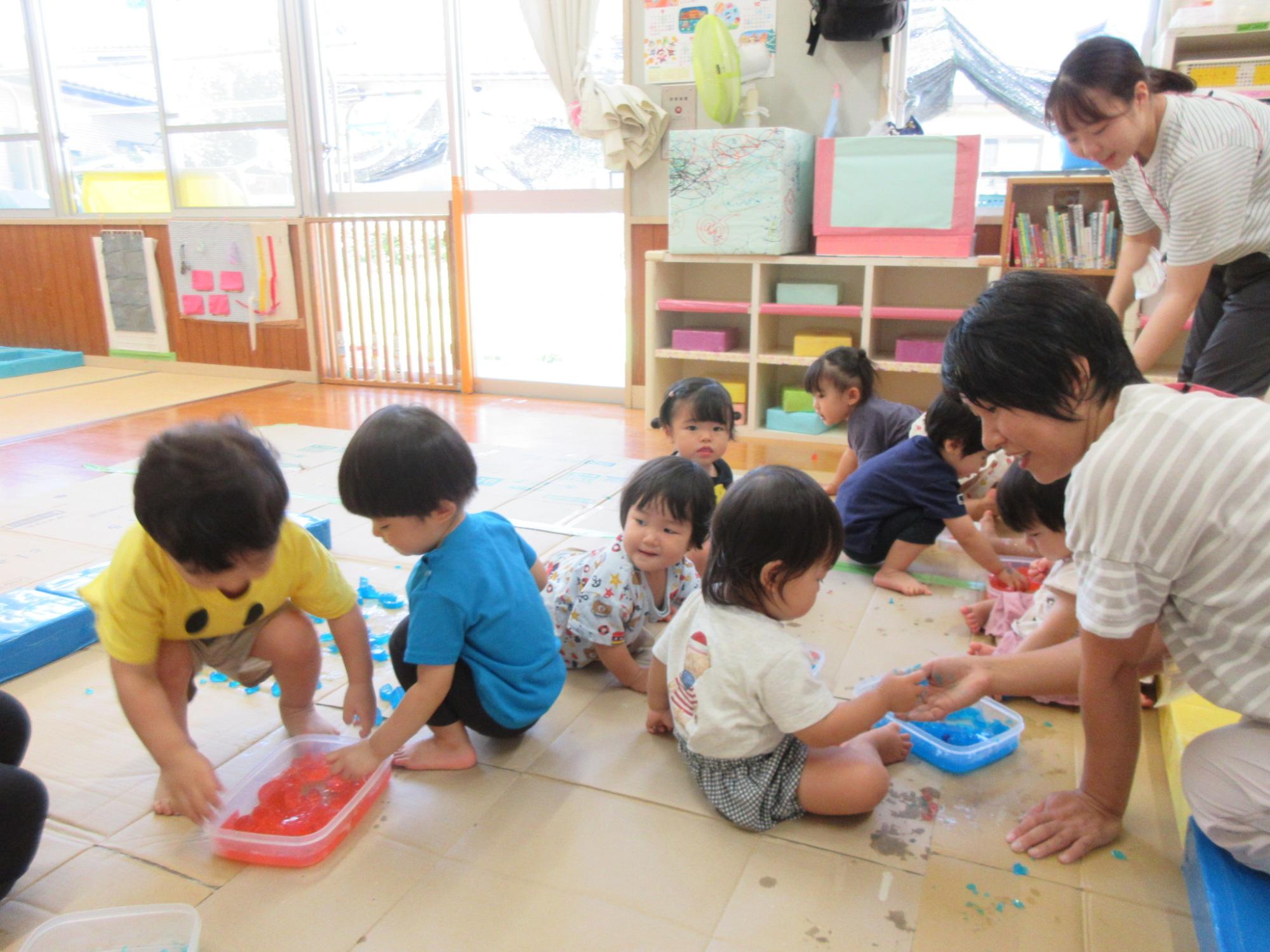 赤や青の色が付いた寒天で遊ぶ1歳児