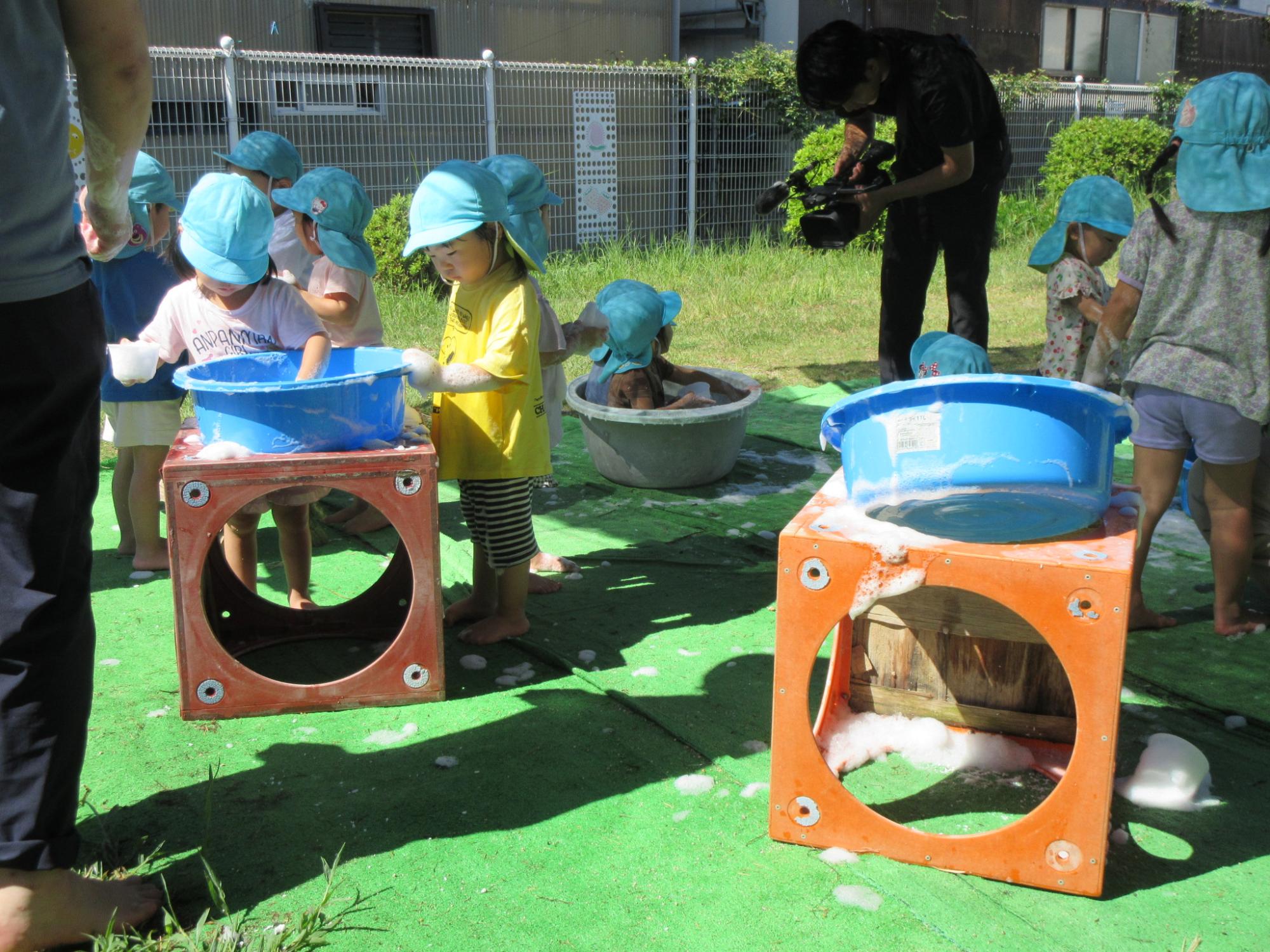 園庭で泡遊びをする2歳児