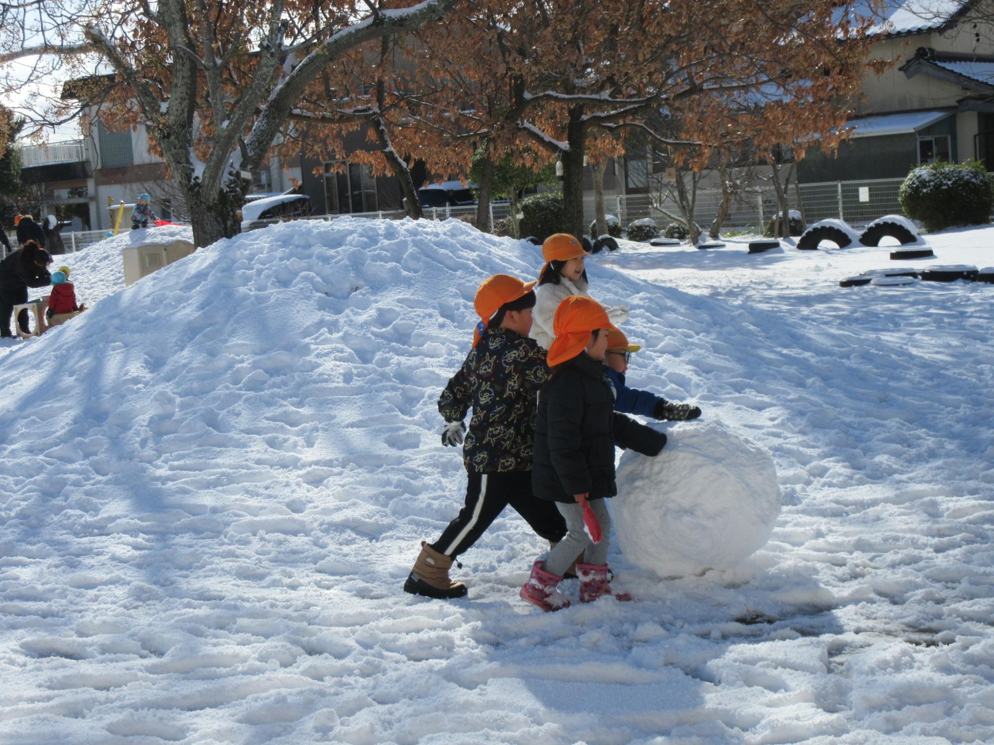 大きな雪玉を作る男の子3人