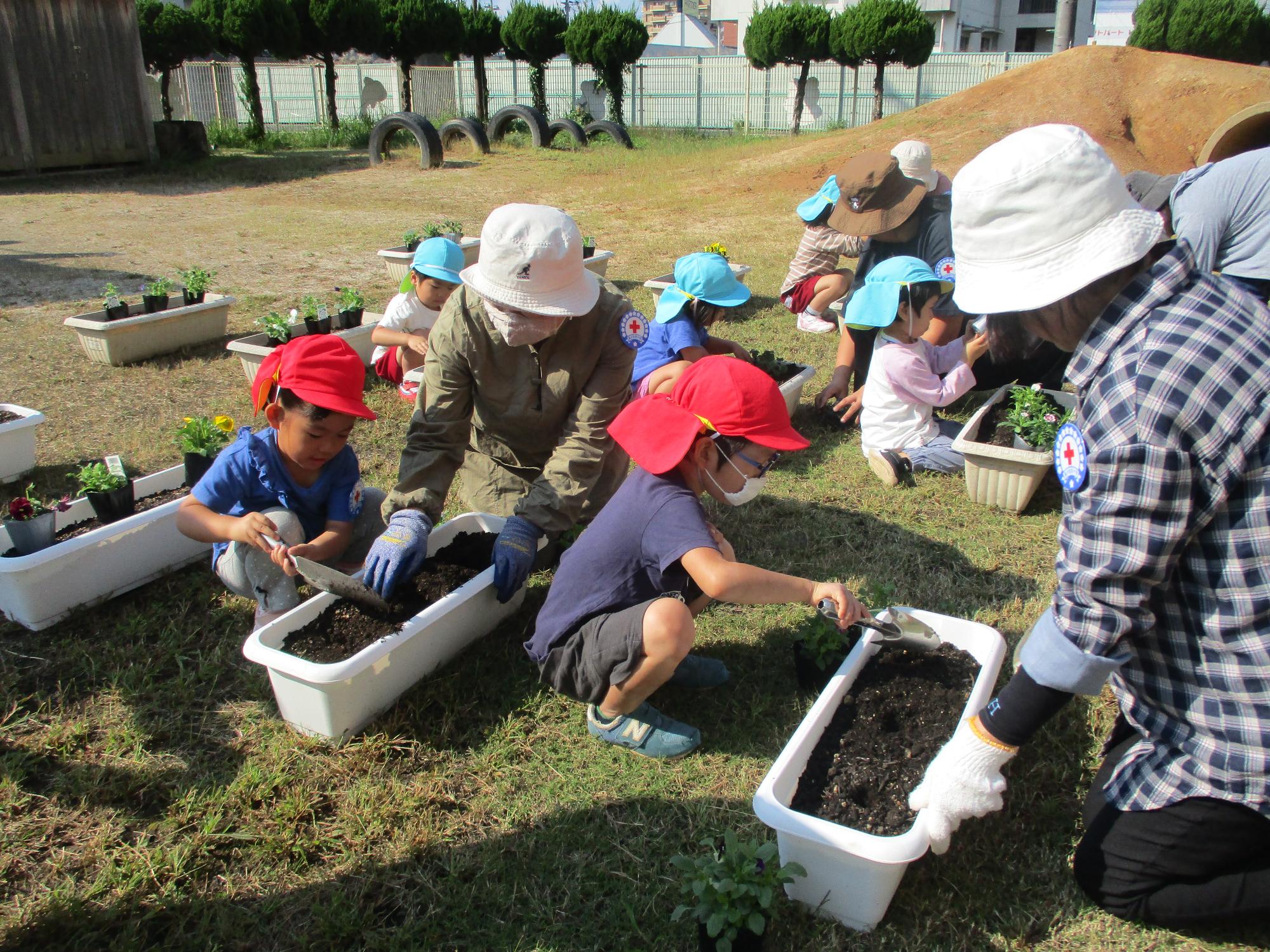 子どもに苗の植え方を教える推進員さん