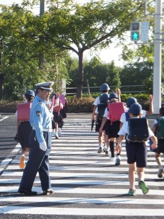 横断歩道を渡る小学生の子供達に通学路で街頭指導をしている写真