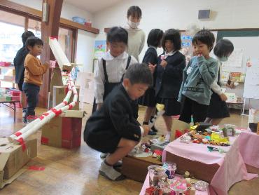 園児が作ったコーナーをのぞき込む小学生と園児