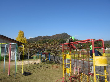 青空と和久羅山の景色と遊具で遊ぶ園児達の写真