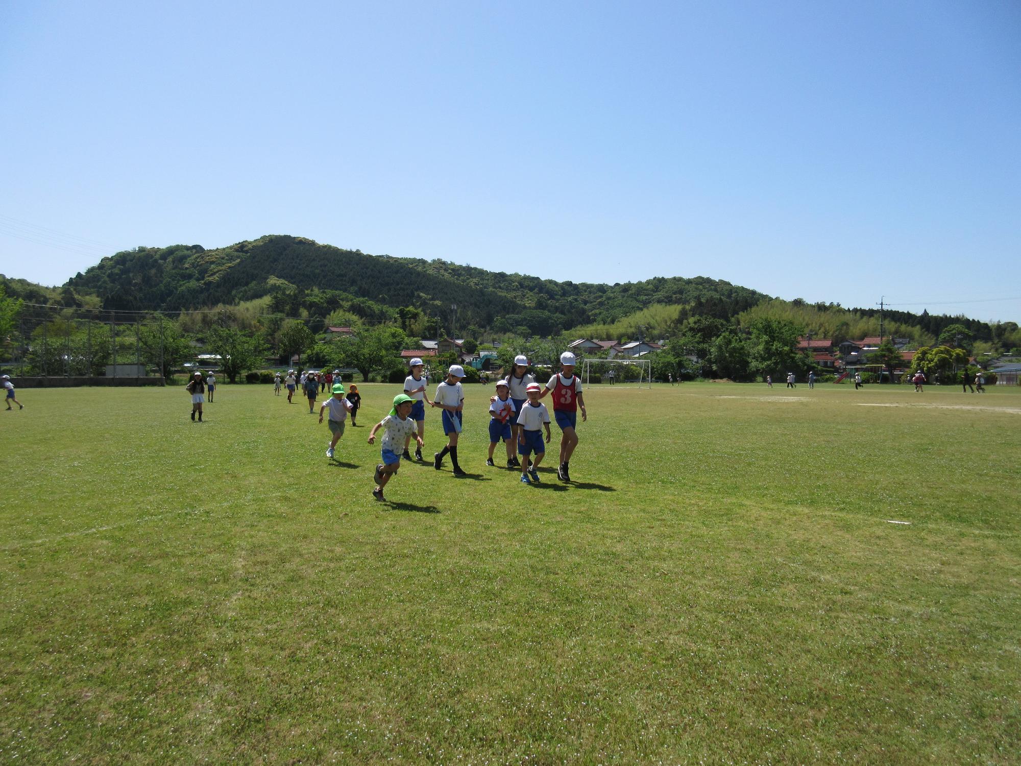 小学校の校庭で朝酌幼稚園のこどもが小学生と一緒にマラソンをしている。