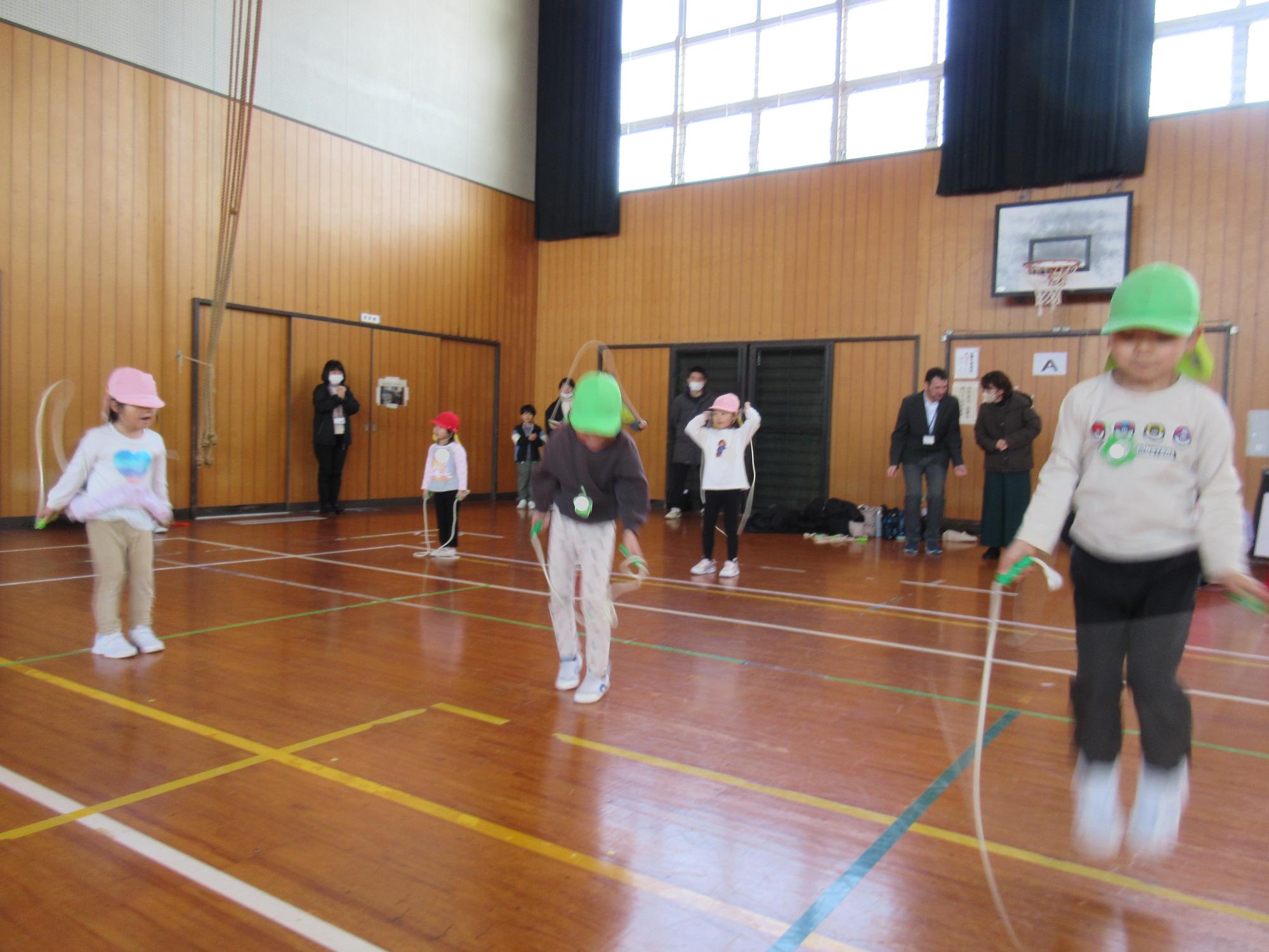 小学校の体育館で、幼稚園のこども達が連続跳びに挑戦している。
