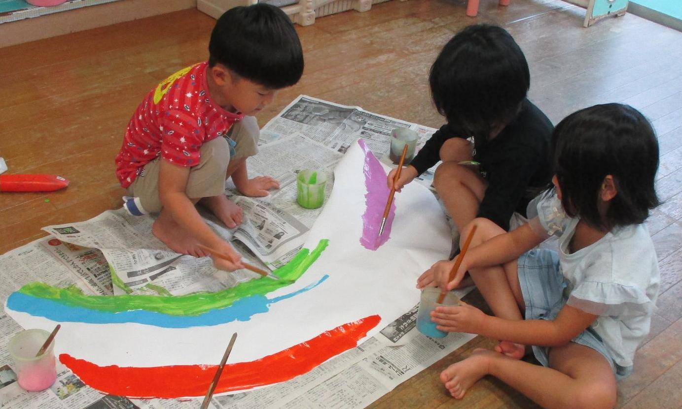 運動会の入場門をにじ色の絵の具で塗るこどもたちの様子