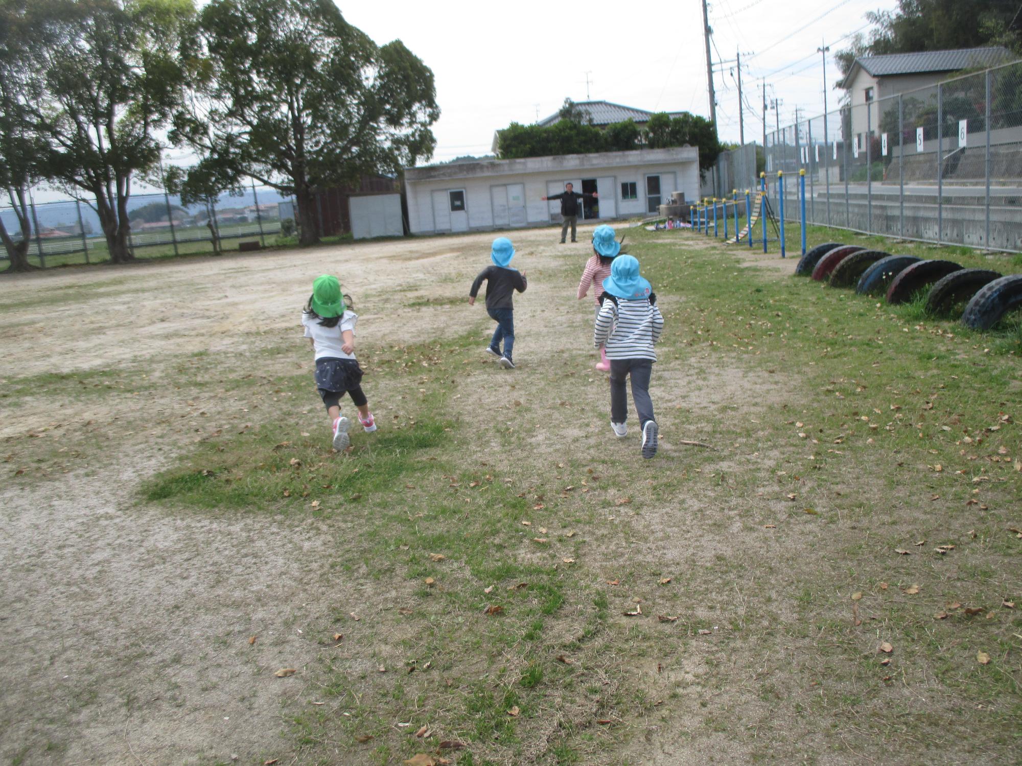 小学校の校庭で元気に走るこどもたち