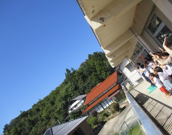 快晴の空に手を振る園児と職員たちの写真