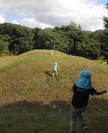 古墳公園敷地内の盛土を駆け上がる園児たちの写真