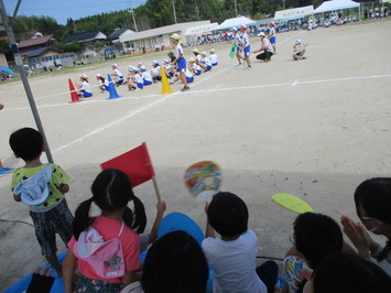手製の応援グッズを手に運動会の競技を観戦する園児たちの写真