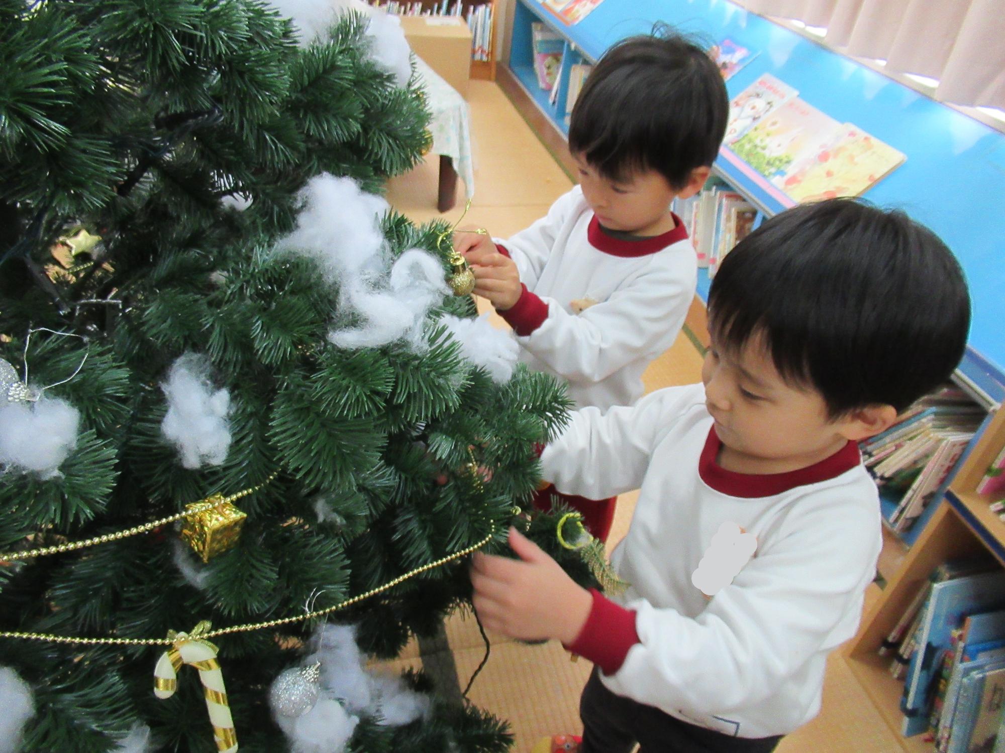 子どもたちがクリスマスツリーに飾りをつけています。