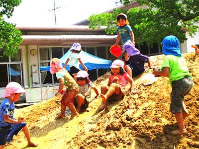 出雲郷幼稚園の園庭にある盛り土の山で遊んでいる園児たちの写真