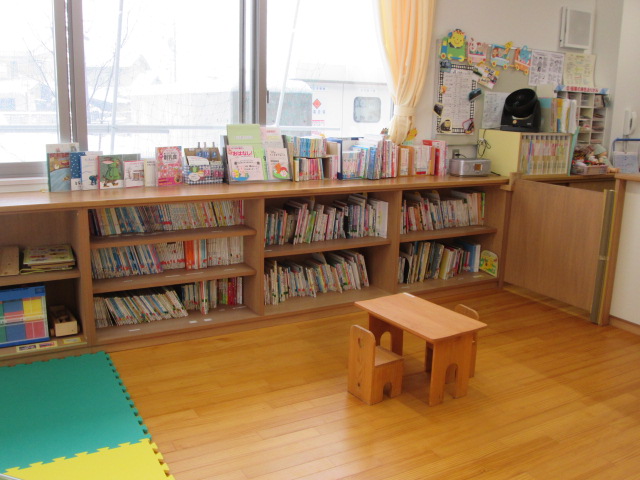 テーブルと椅子があり、本棚に沢山の絵本がある宍道子育て支援センターのあそび場の写真