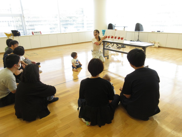大型絵本「だるまさんが」を見る親子