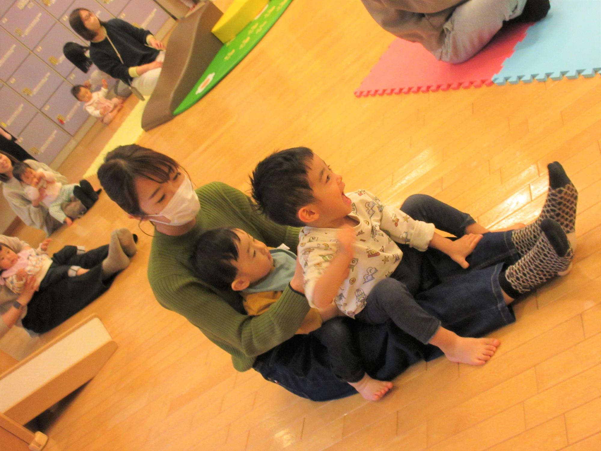 母の膝に兄弟で座って、ふれあい遊びを楽しむ姿