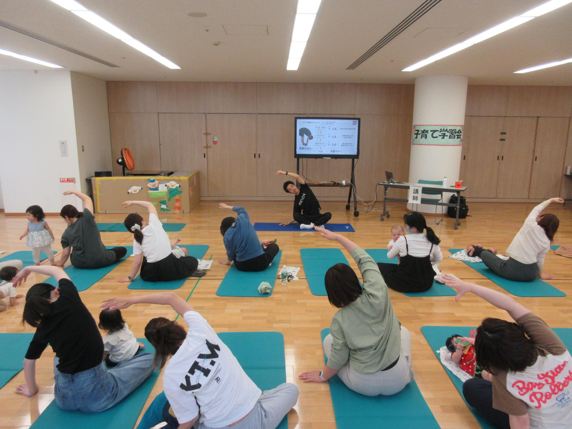 子育て学習会で肩のストレッチを行う参加者