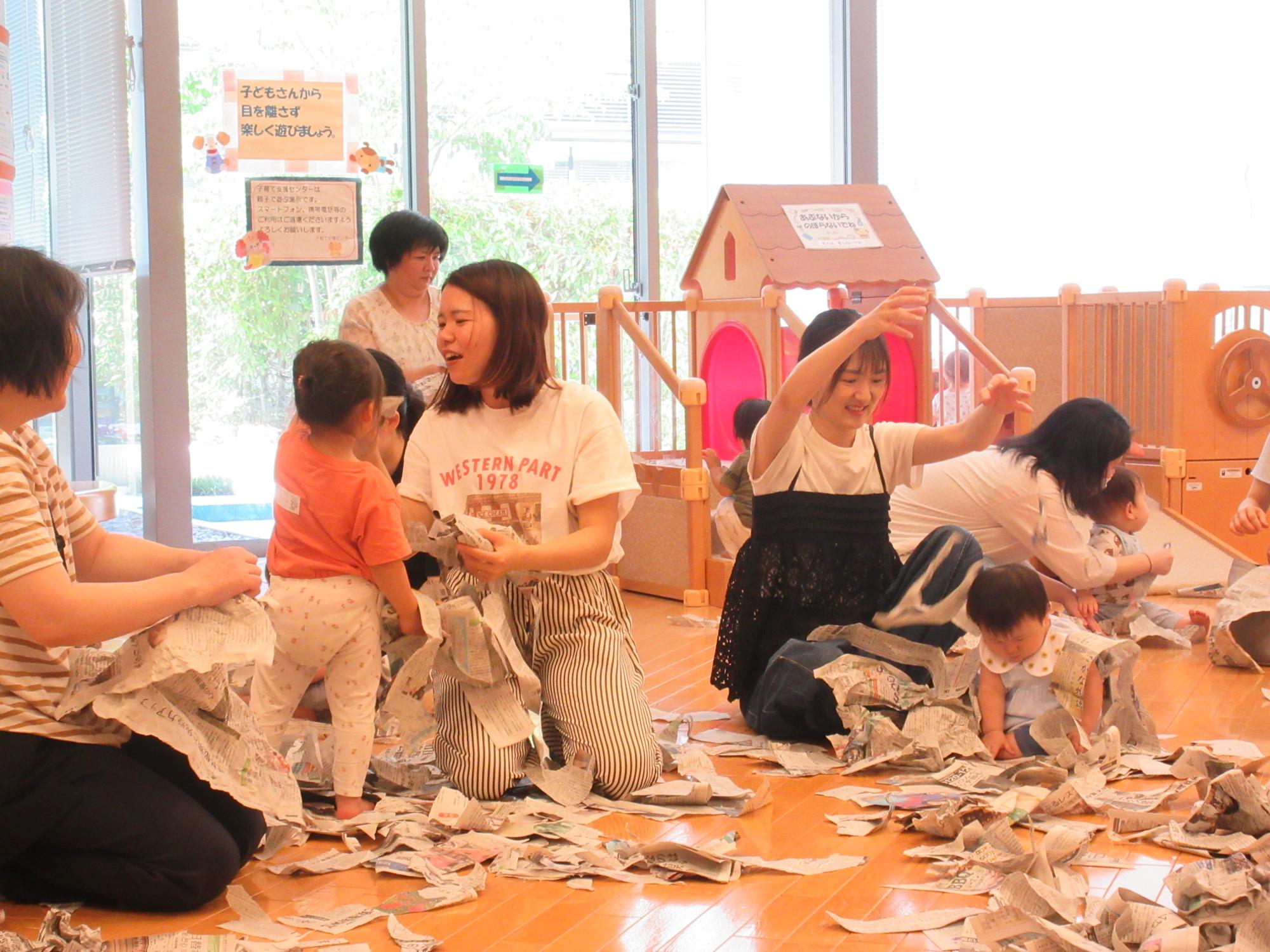 新聞紙をぐしゃぐしゃしたり、破いたり、親子で遊んでいる様子