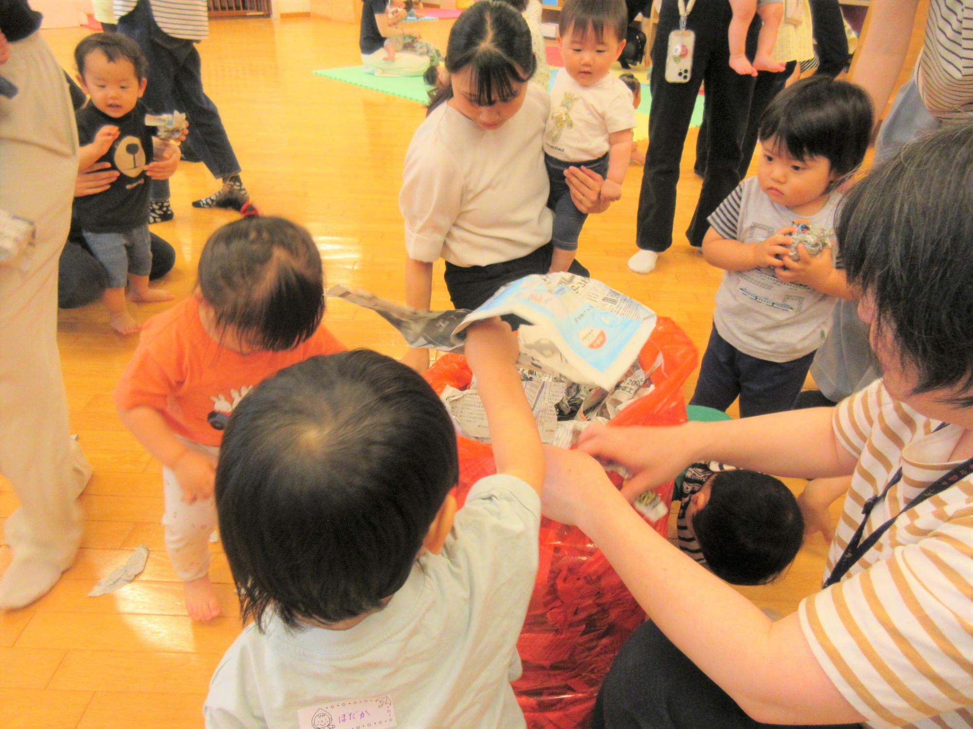 遊んだ新聞をみんなで集めてポリ袋に入れ、お片付けしている姿