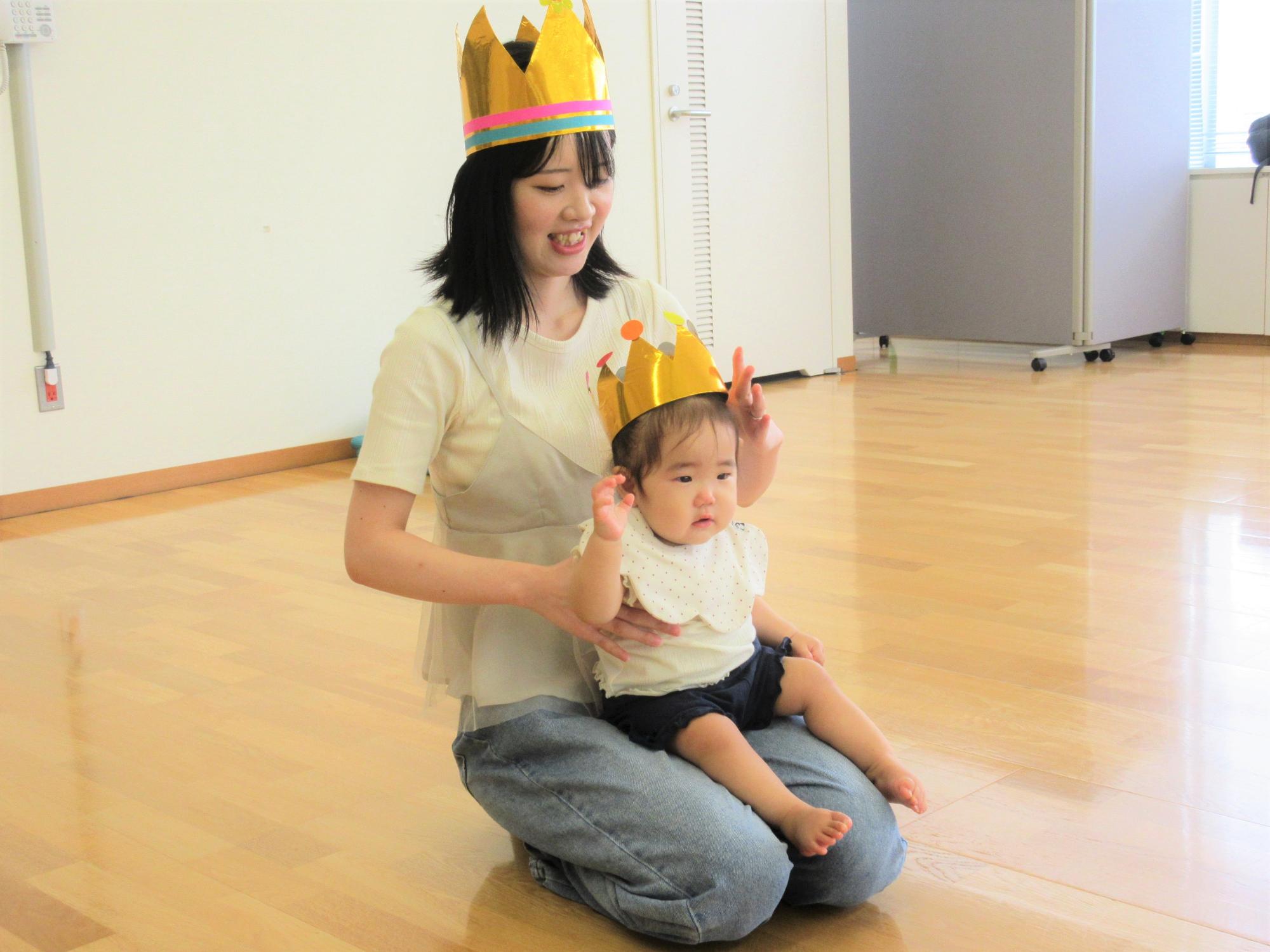 今月卒業するお母さんとお子さん、手つくりの冠をかぶって記念写真