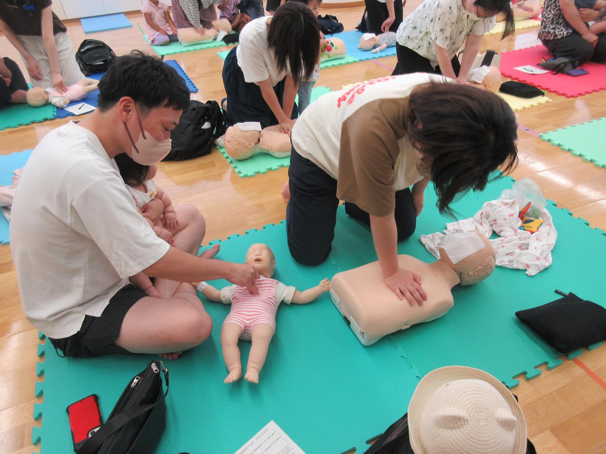 7月の子育て学習会でダミー人形を使って心肺蘇生法をする参加者