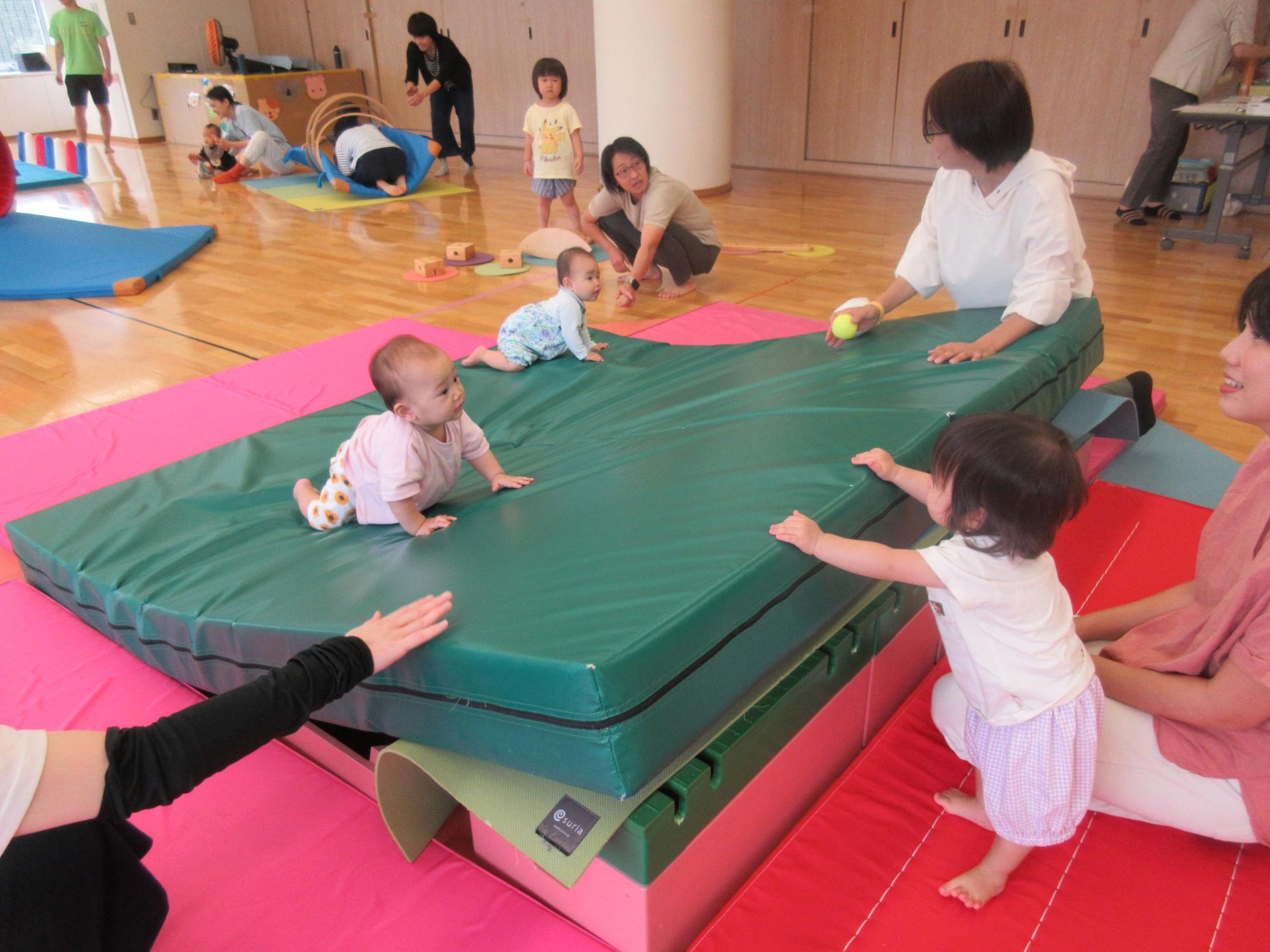 マットの山でハイハイをするこども