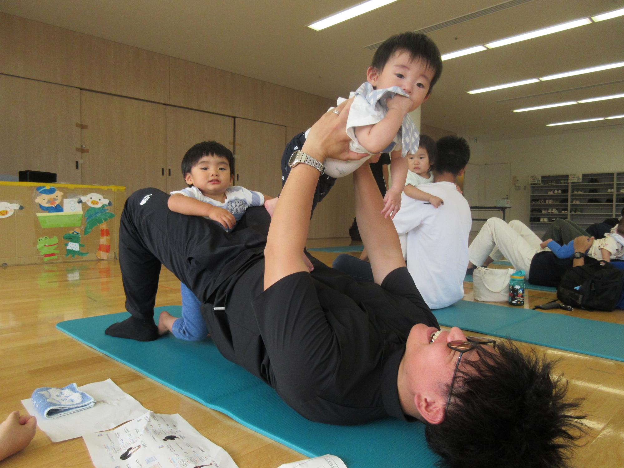 お父さんがこどもと一緒に筋トレをする様子