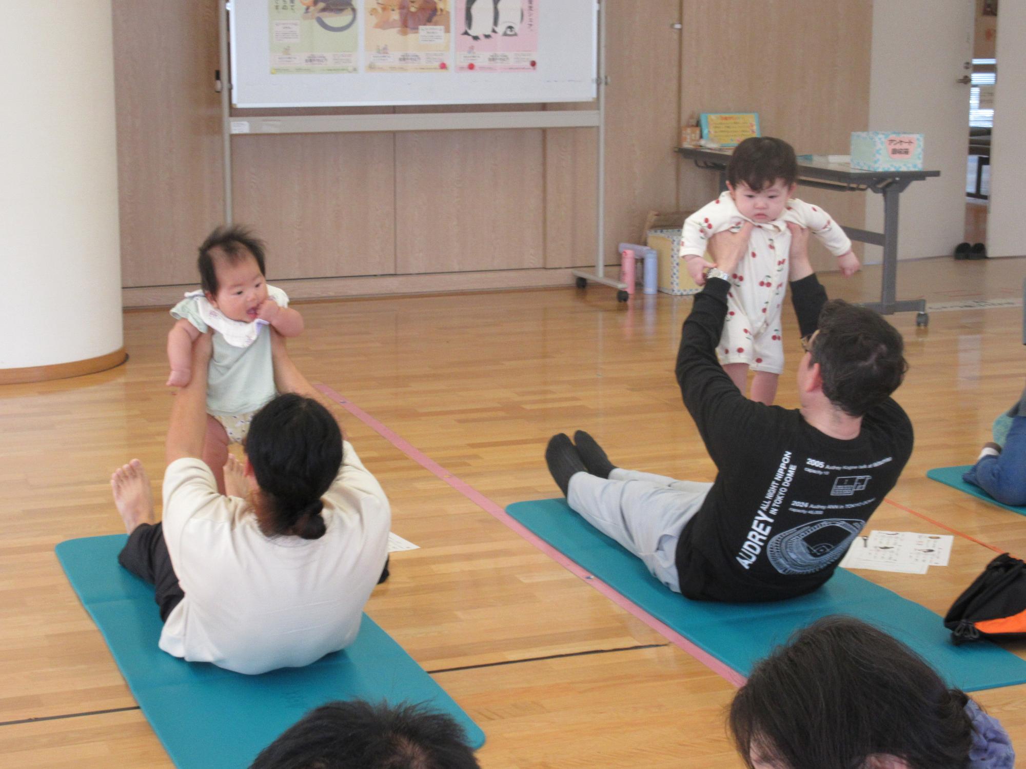 赤ちゃんを抱っこしながら筋トレをするお父さん